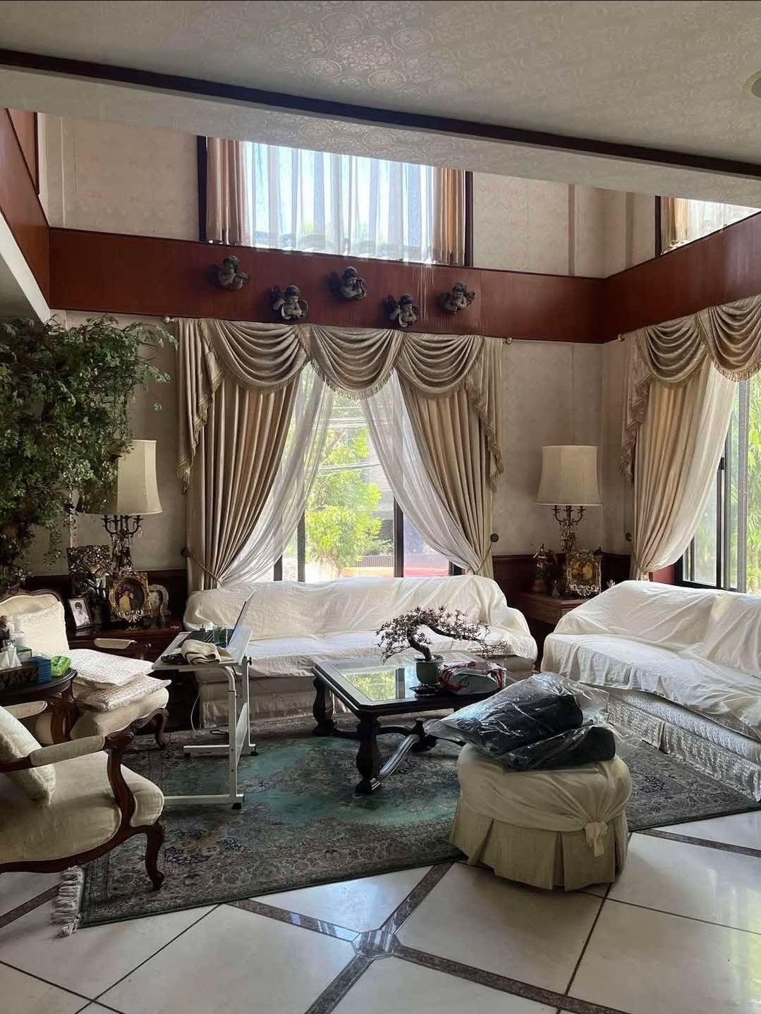 Bright formal living room with double-height windows and elegant draperies