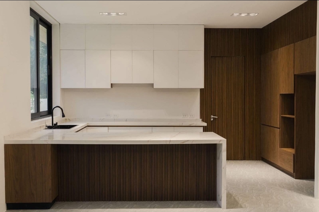 Clean kitchen with marble waterfall counter and fluted walnut cabinetry
