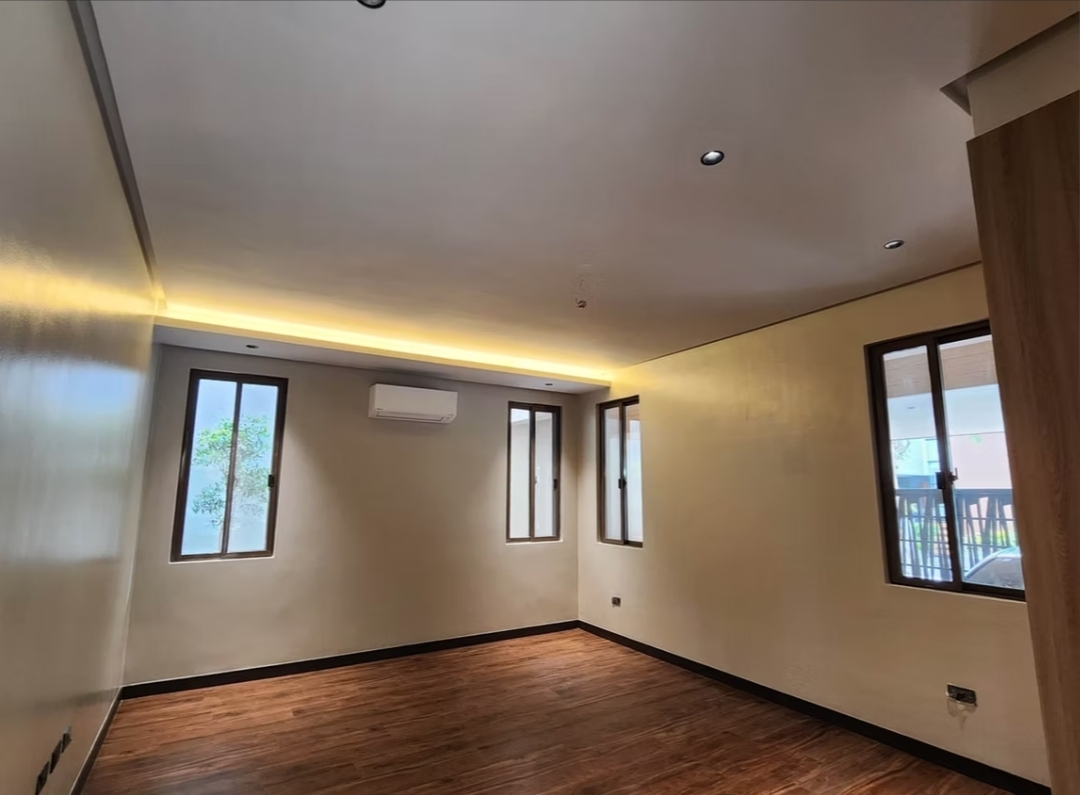 Bedroom with warm wood flooring, cove lighting, and split-type A/C