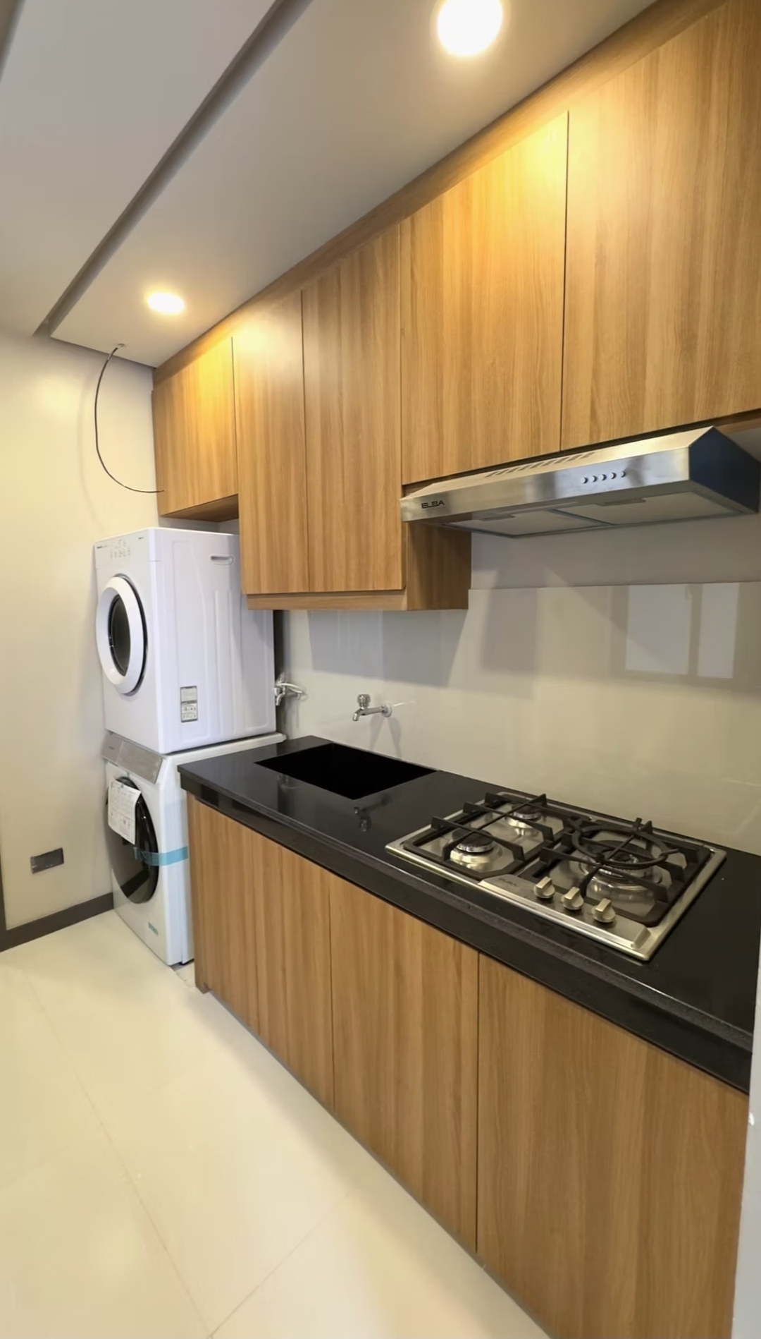 Daily kitchen with gas hob, rangehood, and stacked front-load washer & dryer