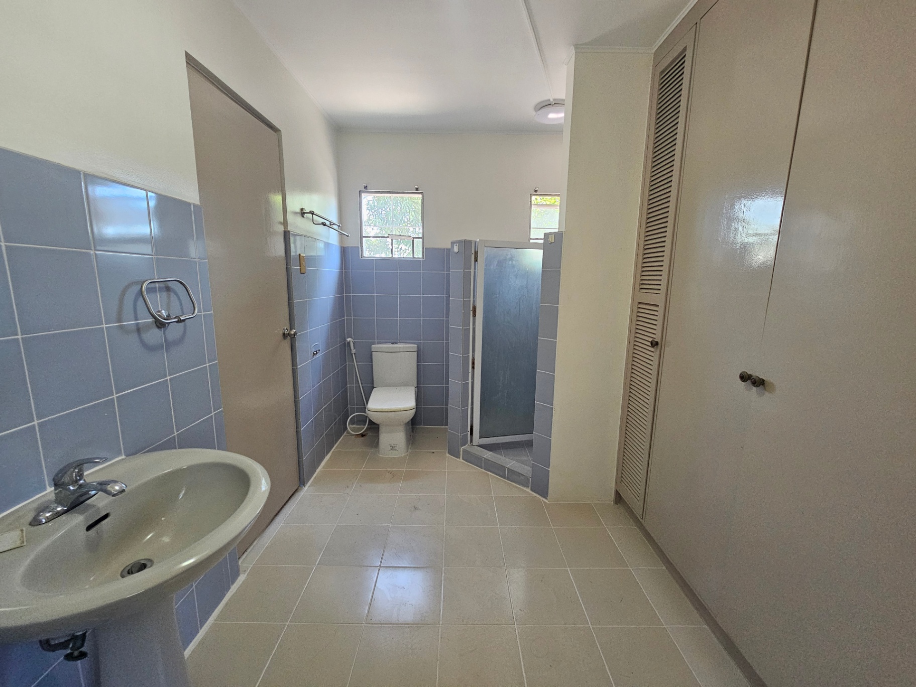 Bathroom with blue wall tiles, toilet, and glass shower partition
