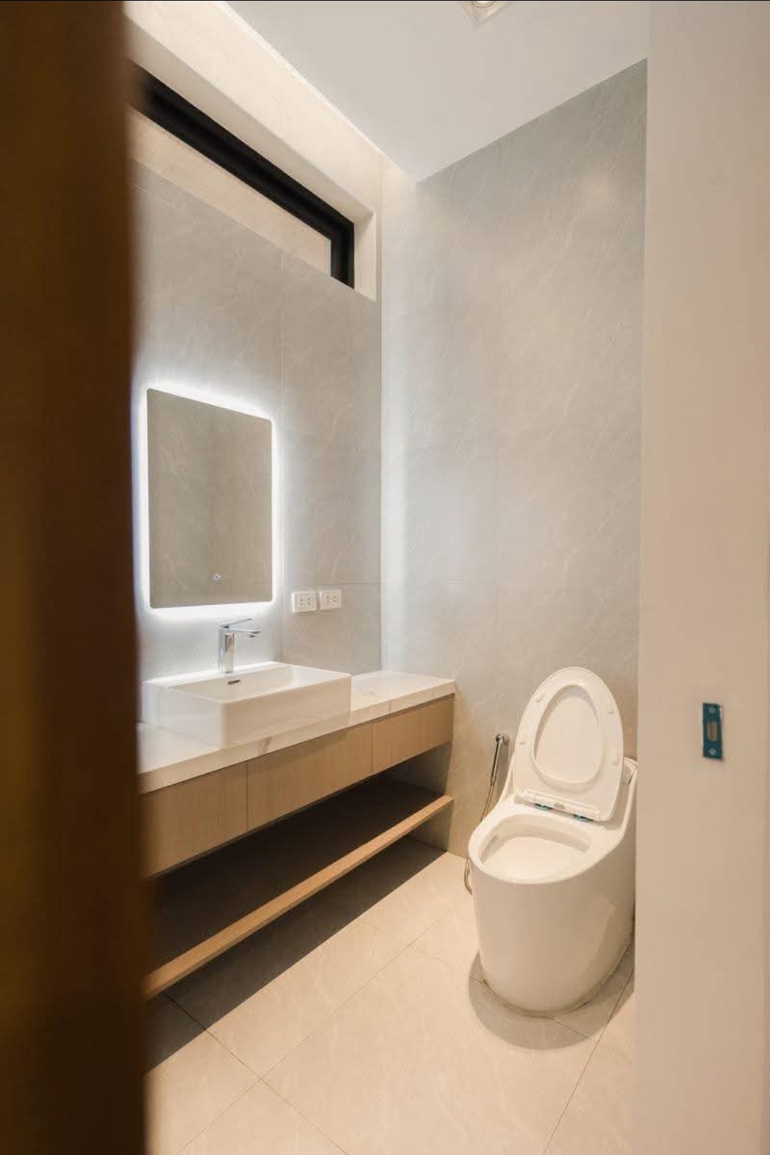 Powder room with backlit mirror, vessel sink and stone tiling