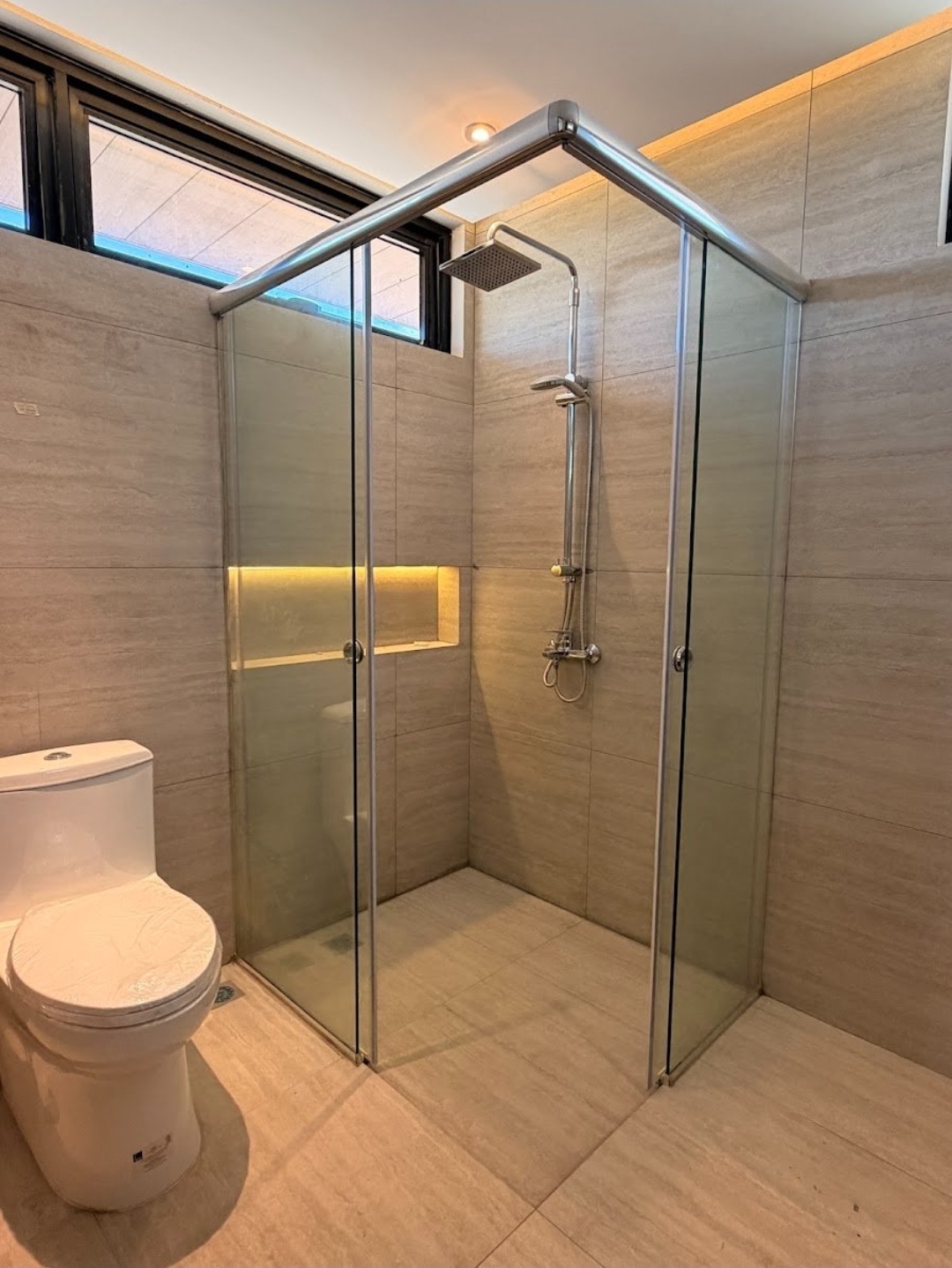 Modern bathroom with glass shower enclosure and stone-look tiles