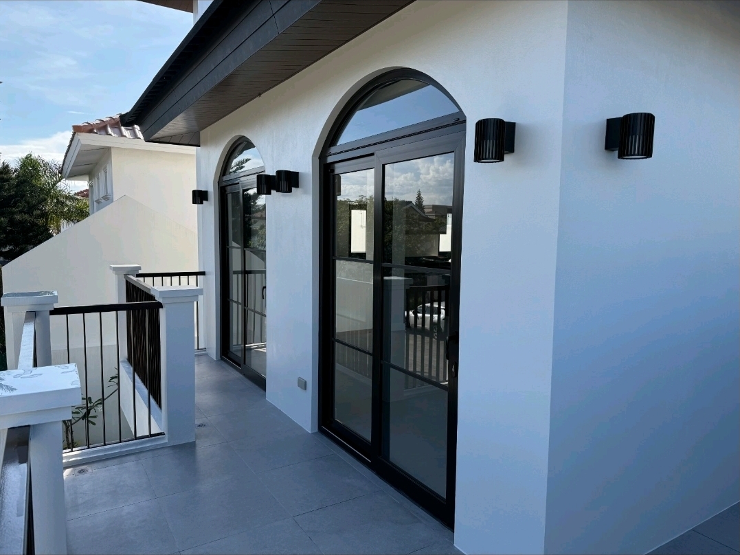 Second-floor balcony with tall arched sliding doors and black wall sconces