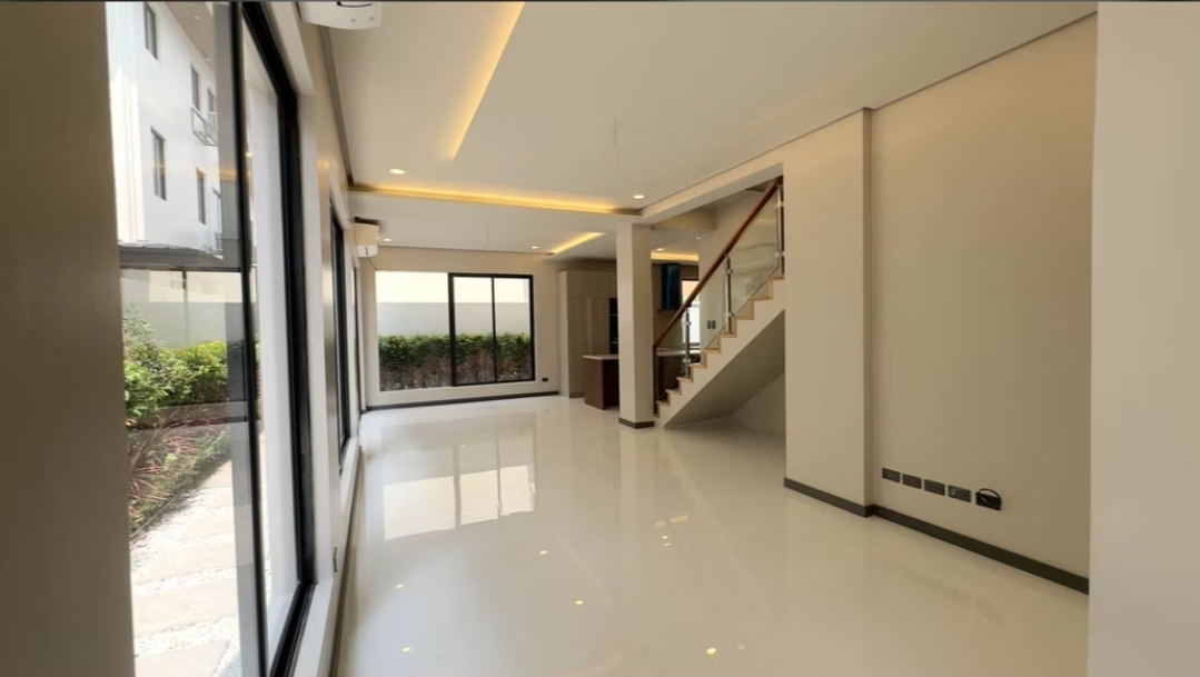 Open living area with cove lighting and open-riser staircase