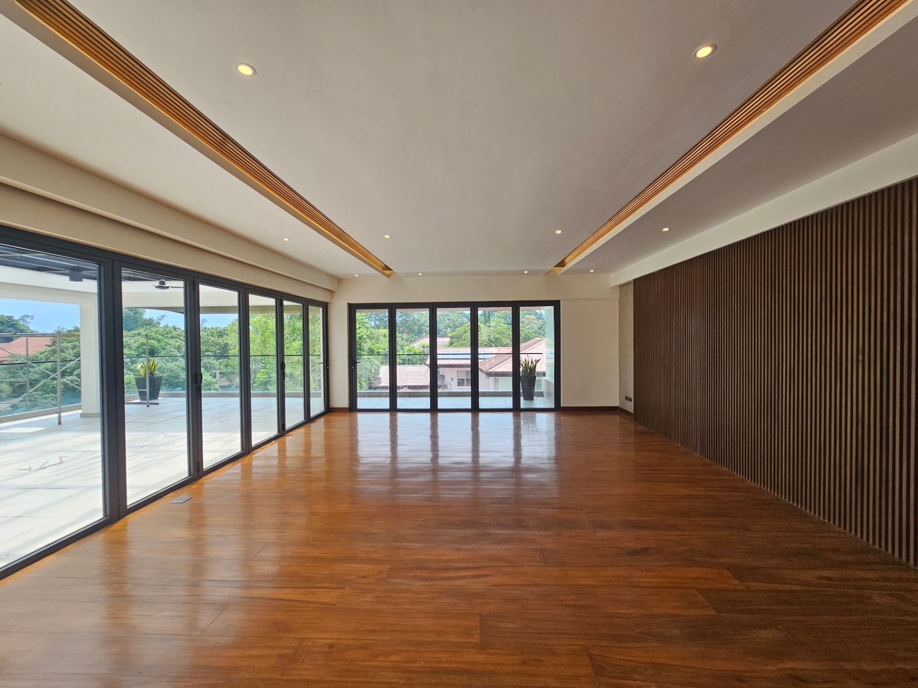 Bright room with full glass wall opening to a covered terrace