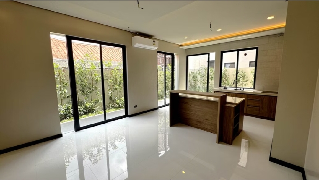 Kitchen and dining area with island and wall of sliding glass to garden