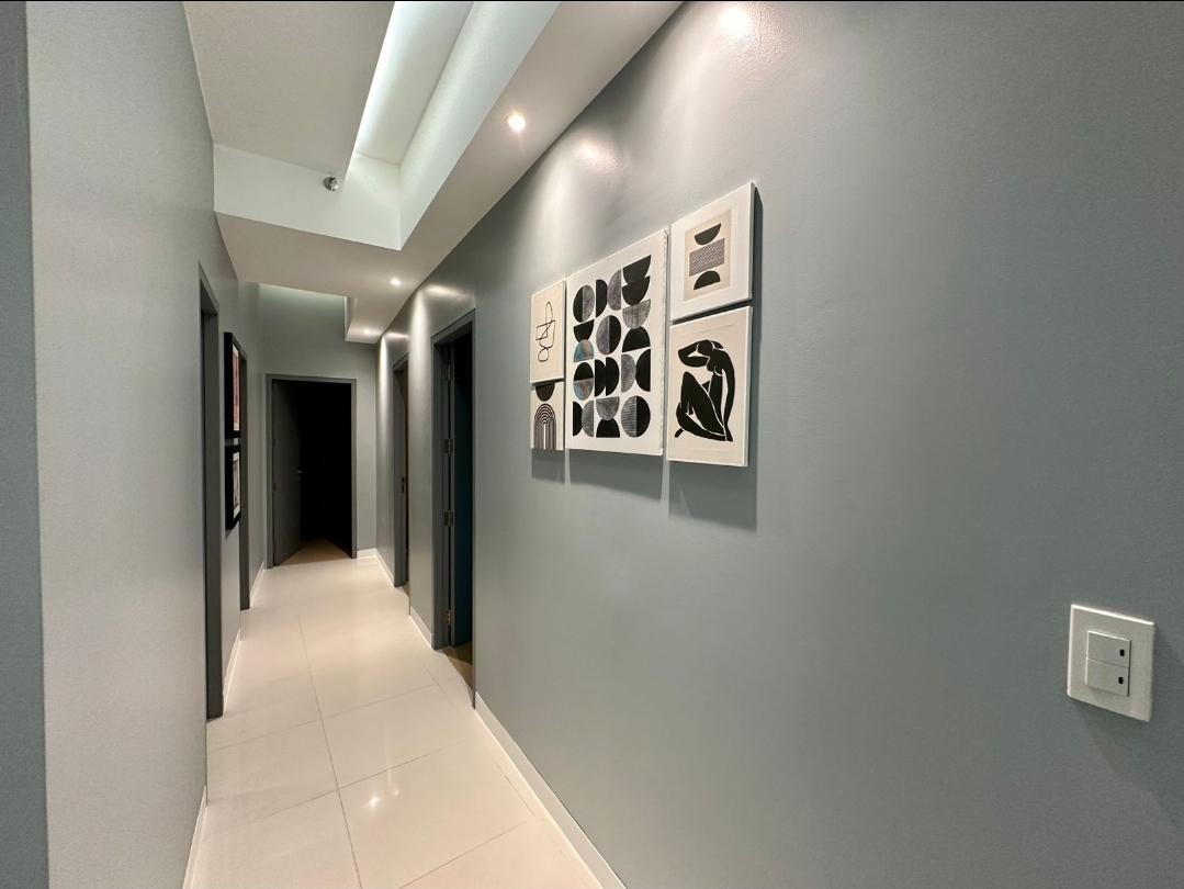 Bedroom hallway with framed artwork and cove-lit ceiling