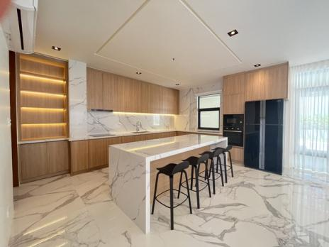 Show kitchen with marble waterfall island, wood cabinetry and bar seating