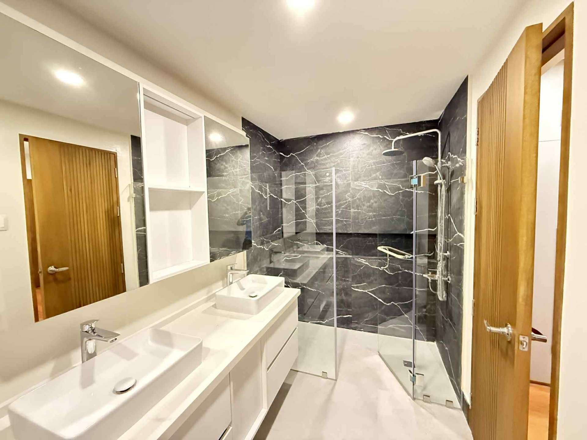 Marble bathroom with walk-in glass shower and dual vessel sinks