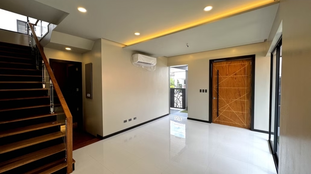 Bright entry foyer with wood pivot door and glass-railed staircase