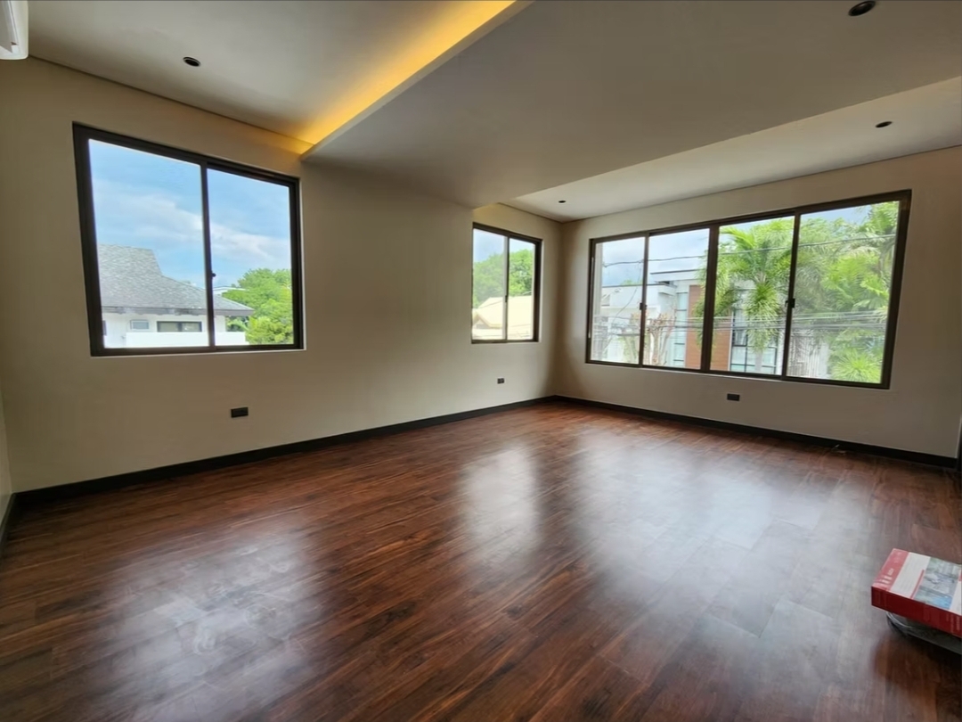 Spacious master bedroom with hardwood floors and dual picture windows