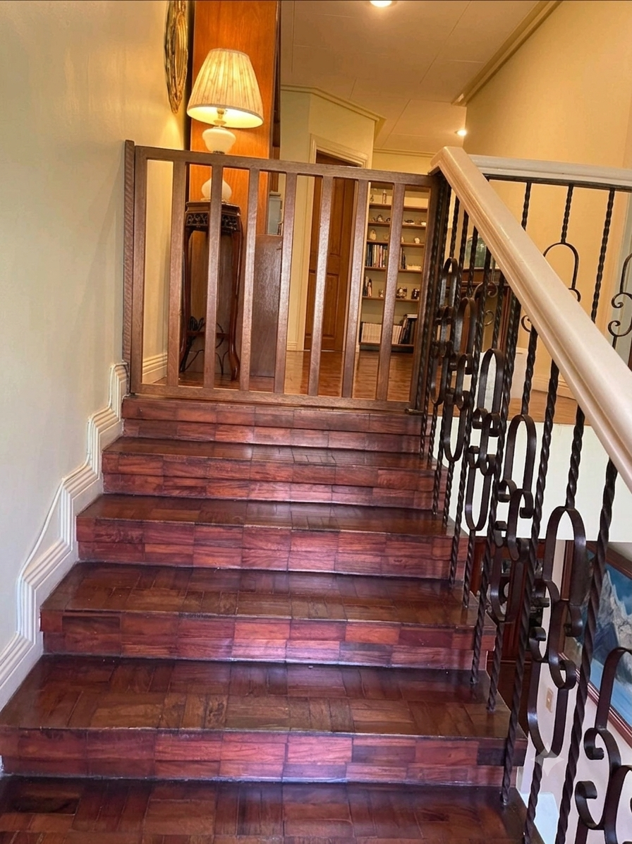 Wood stair landing with wrought-iron balustrade and warm ambient lighting
