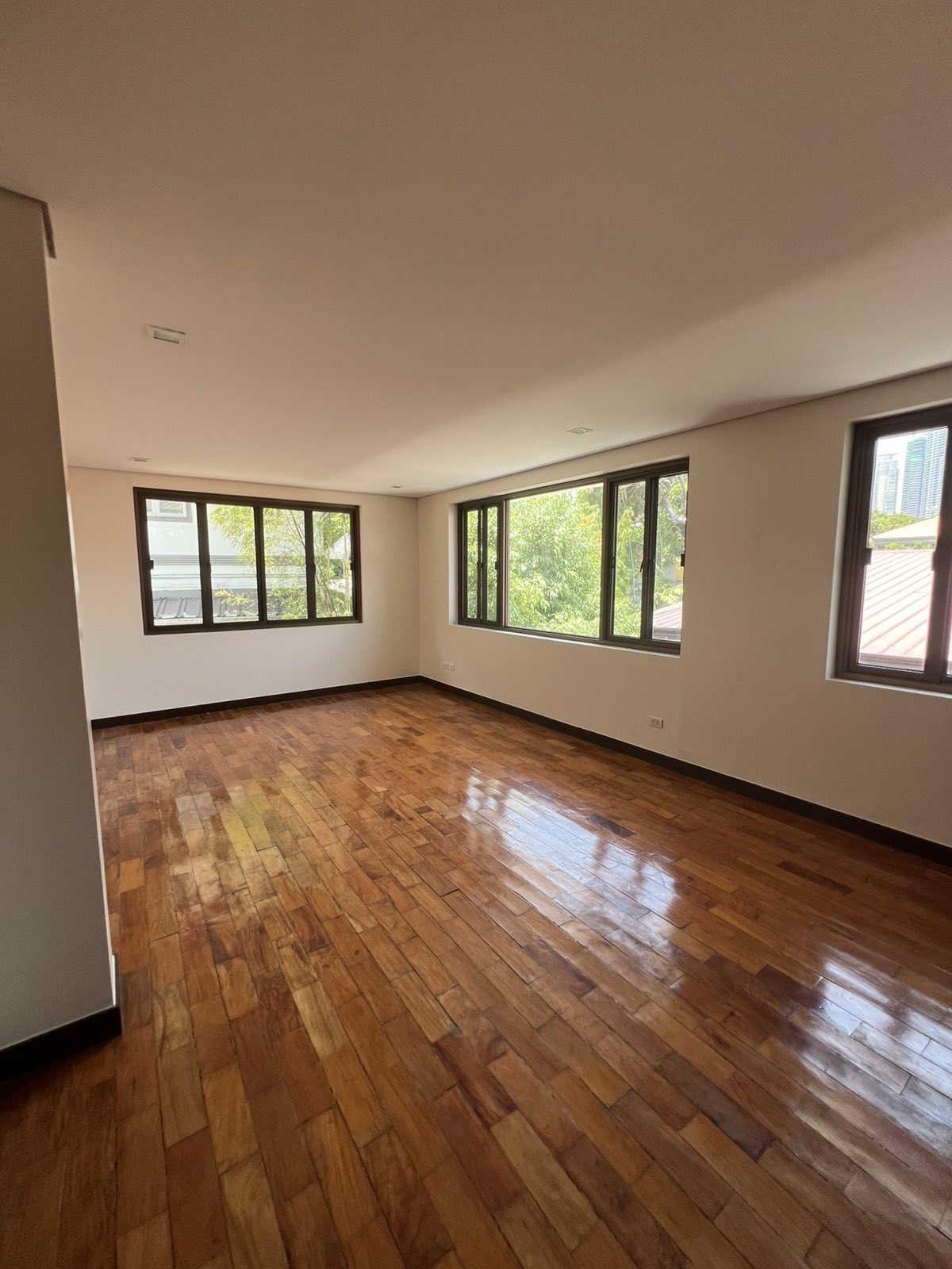 Spacious bedroom with wraparound windows and parquet flooring