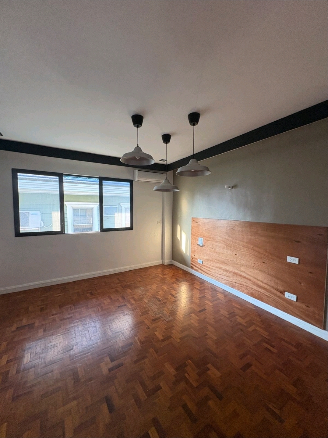 Spacious bedroom with pendant lighting and wood accent wall