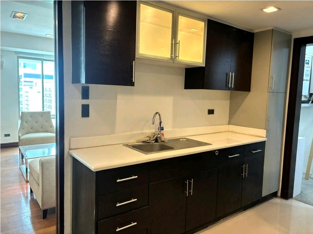 Kitchen counter with sink, dark cabinetry, and glass upper cabinets
