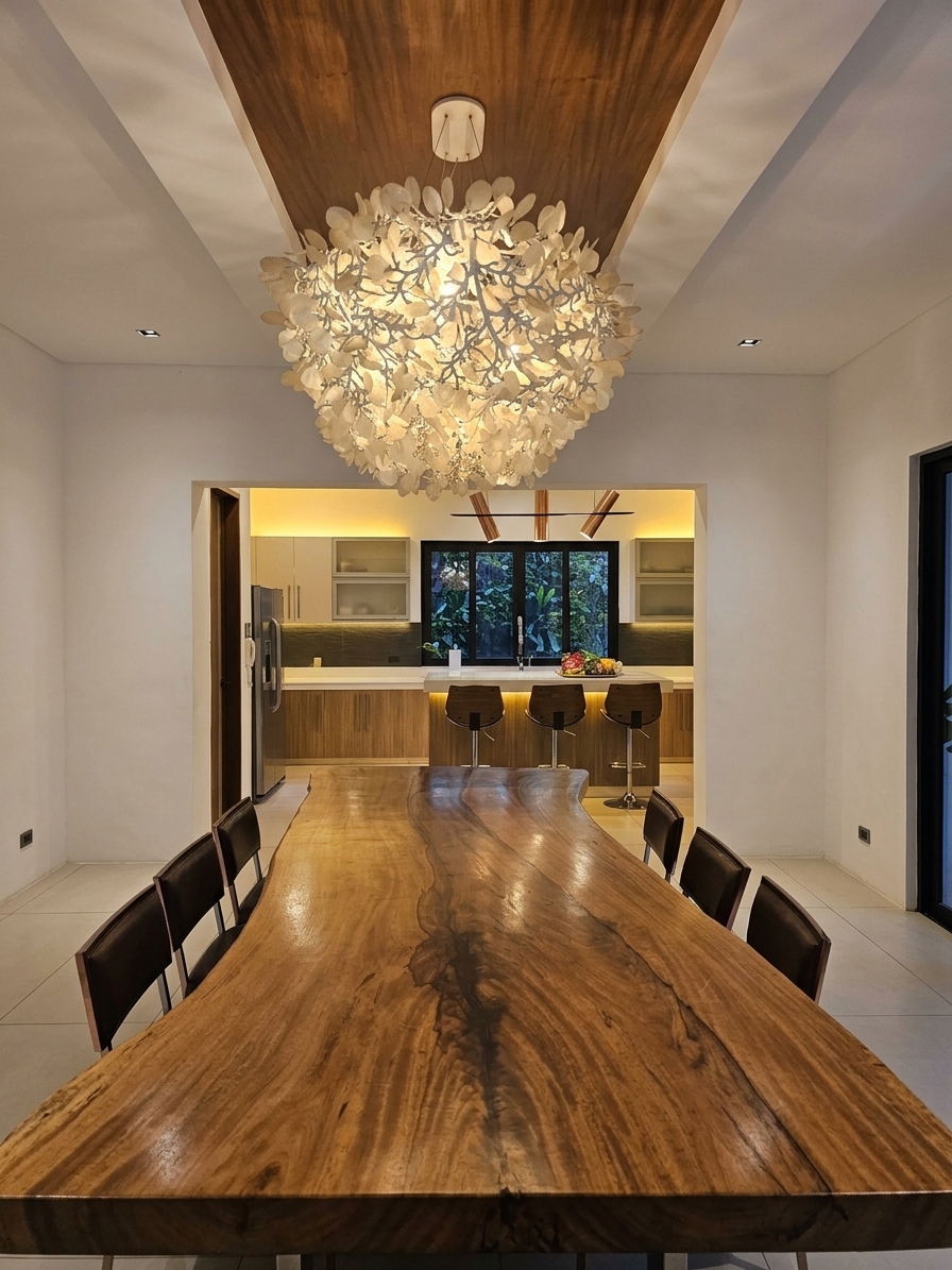 Live-edge dining table beneath a sculptural chandelier with the kitchen beyond