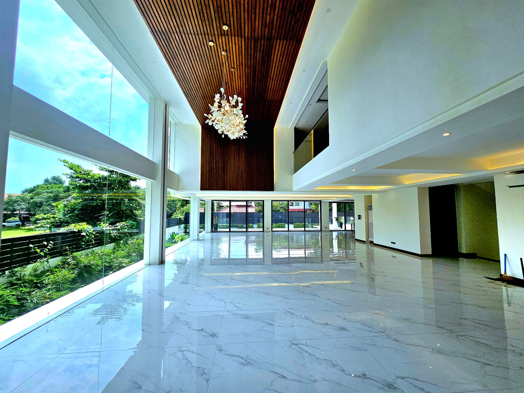 Double-height grand living area with wood-slat ceiling and statement chandelier