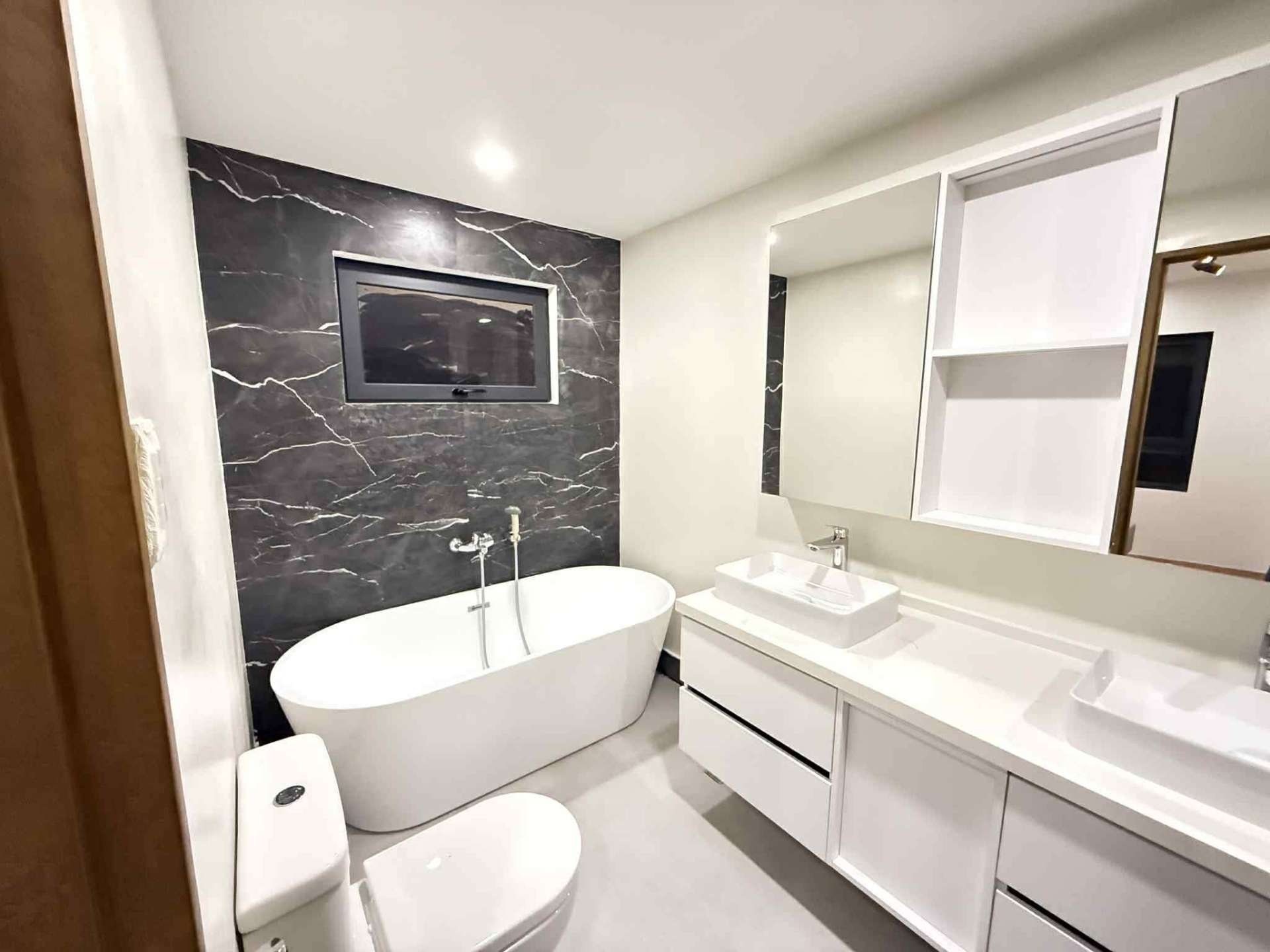 Master bathroom with freestanding tub against a black marble feature wall
