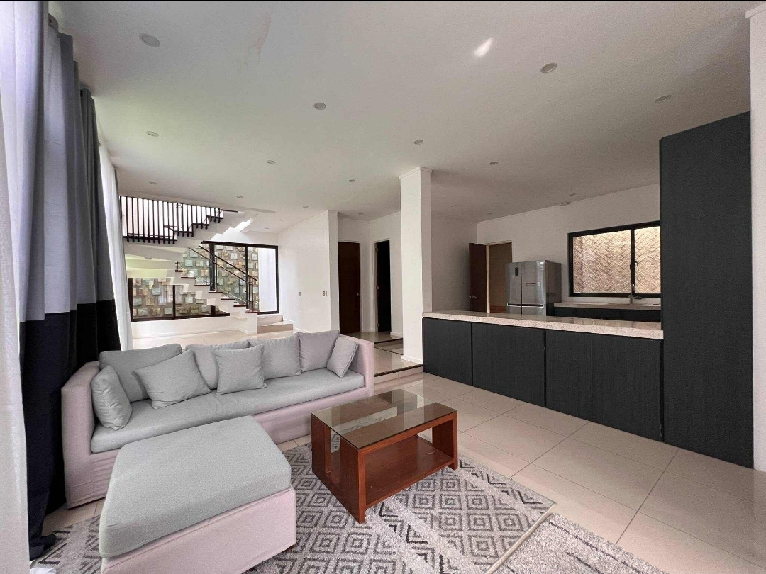 Open living and kitchen area with staircase and semi-furnished pieces
