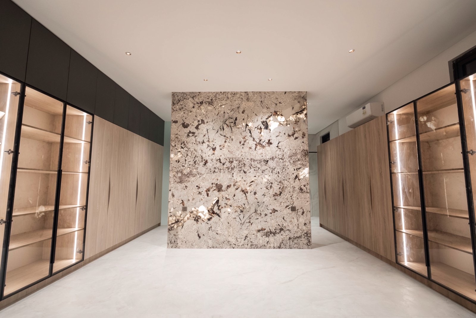 Walk-in dressing room with marble feature wall and lit cabinetry