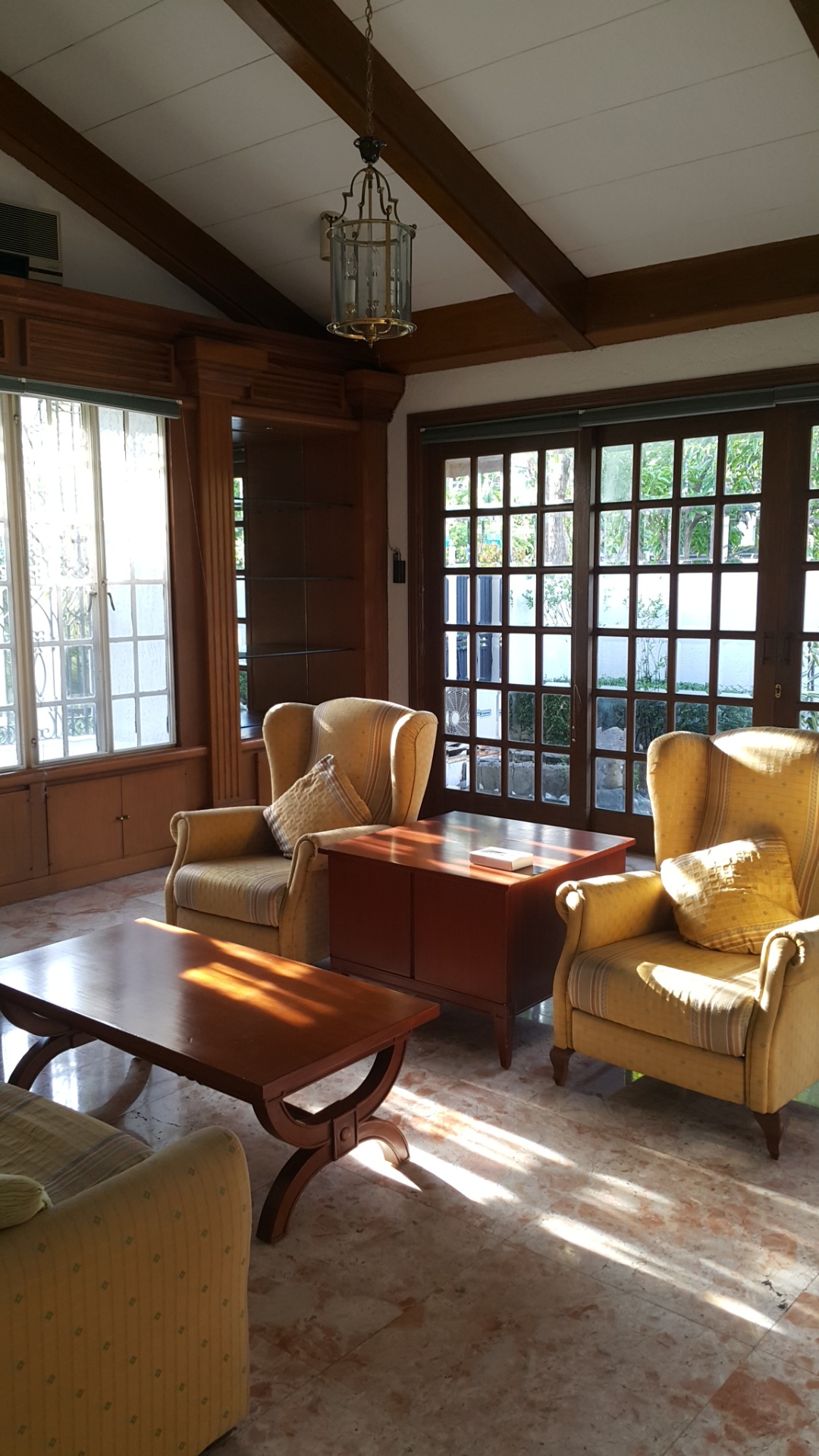 Sunlit garden lounge with wood-framed capiz-style windows