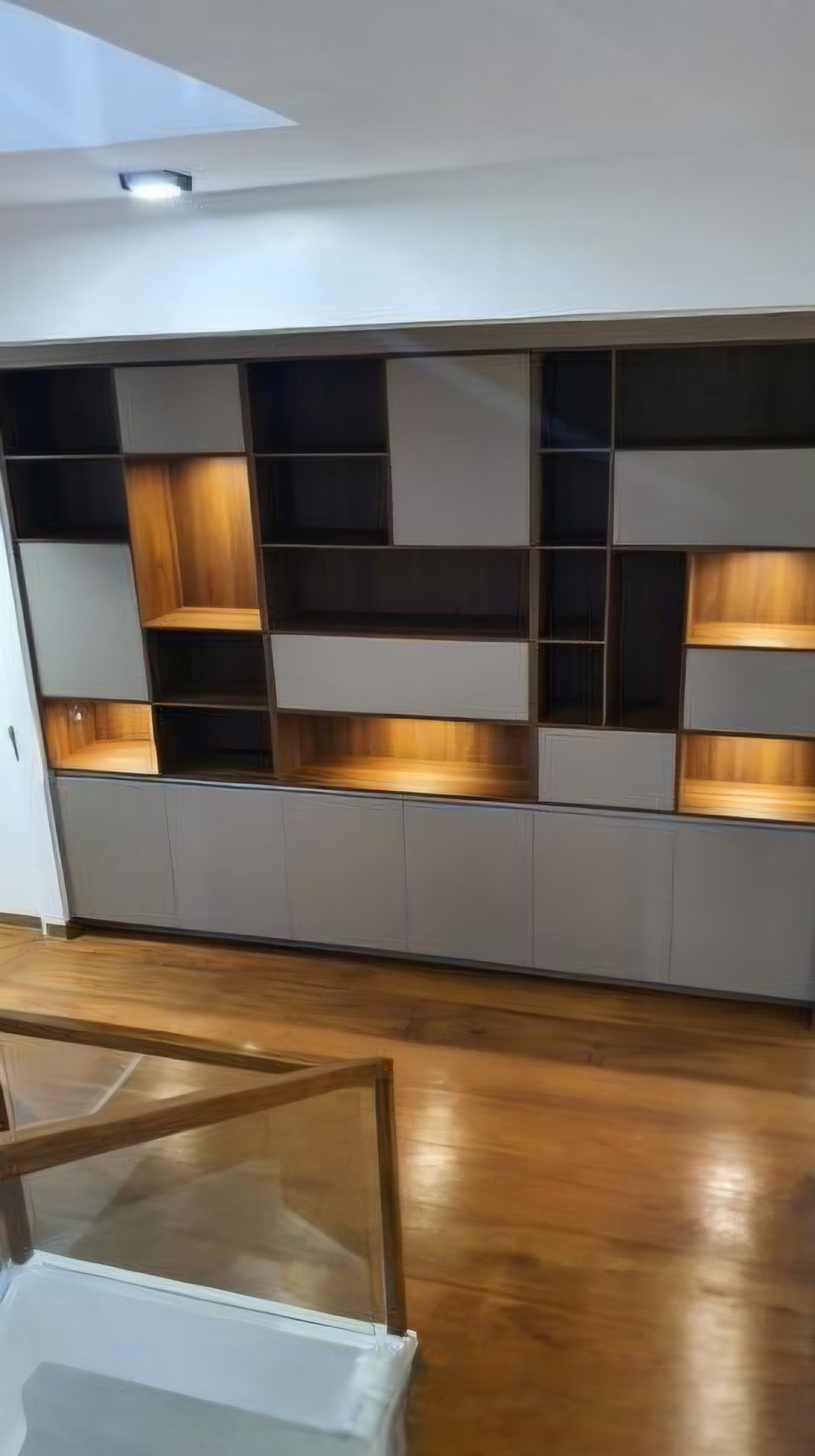 Custom lit built-in shelving wall over hardwood flooring