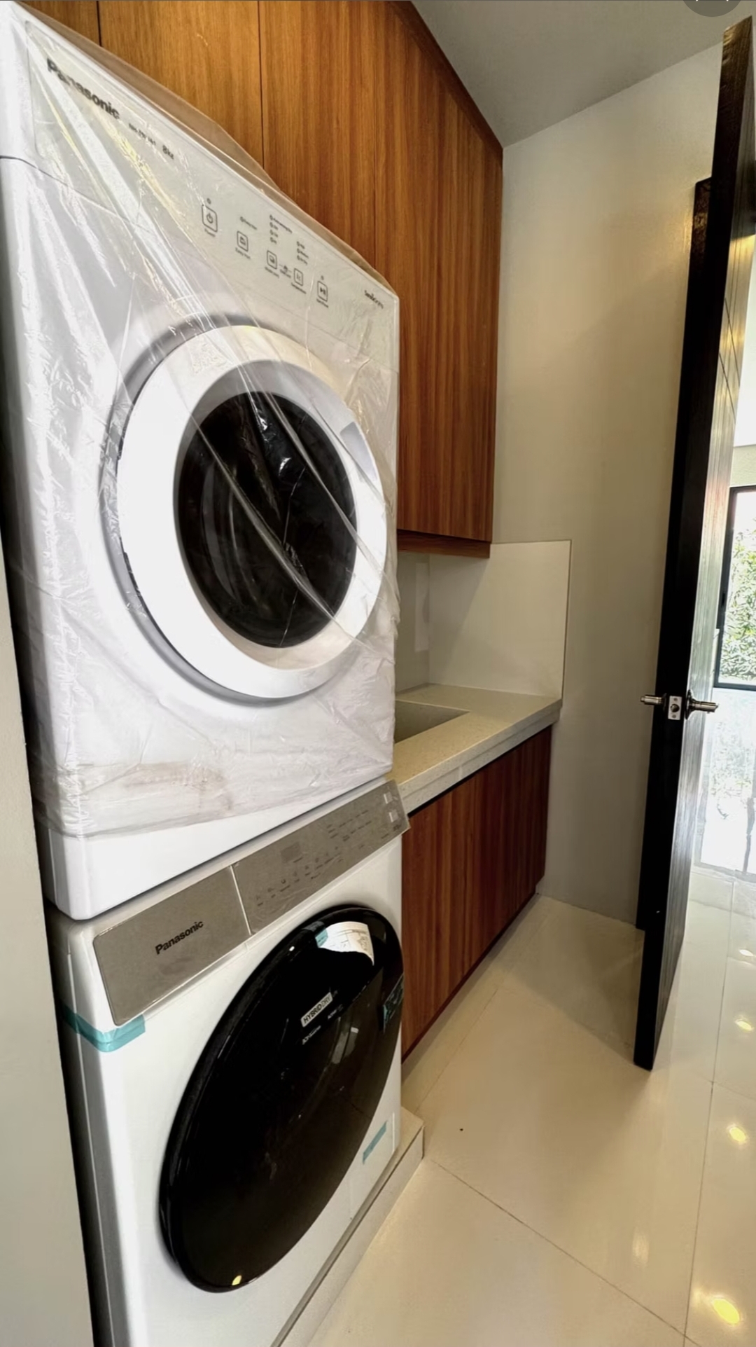 Utility area with stacked front-load washer and dryer, built-in wood cabinetry