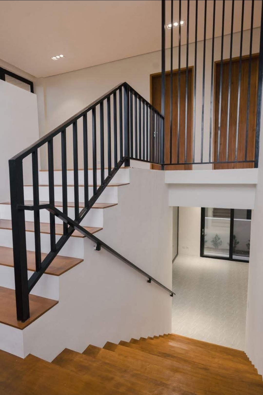 Floating timber treads with black steel balustrade beside a double-height void