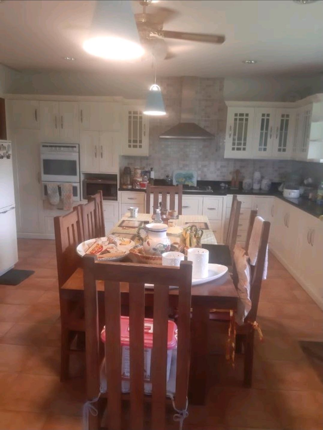 Main kitchen with white cabinetry, granite counters, breakfast dining table and full appliances