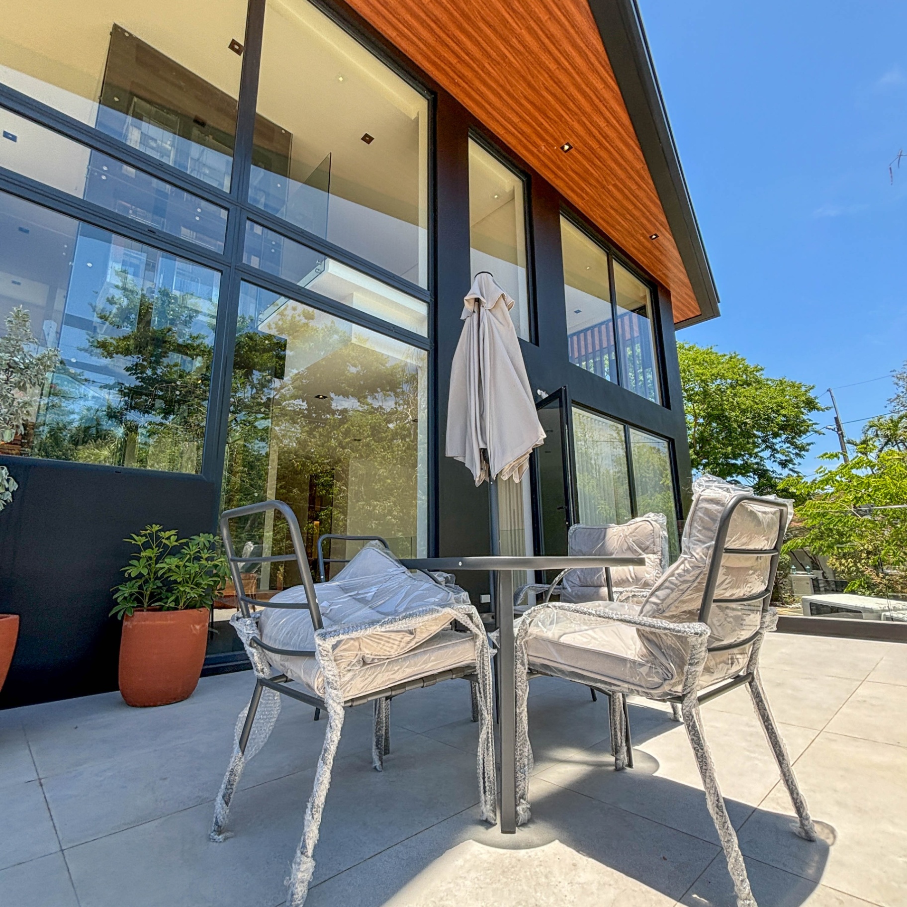 Lanai terrace with outdoor dining set beside full-height glass walls