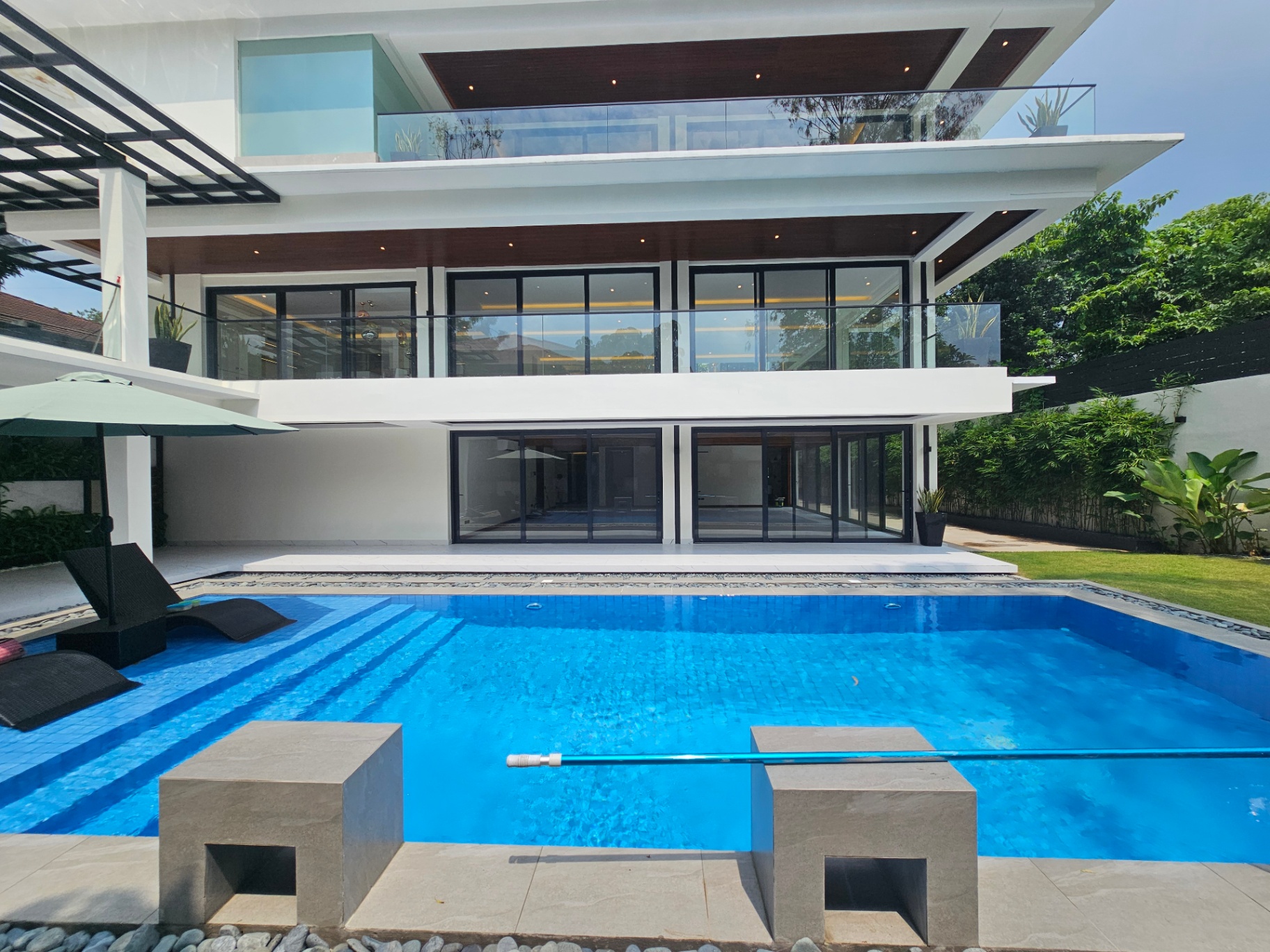 Swimming pool with the glass-wrapped mansion behind it
