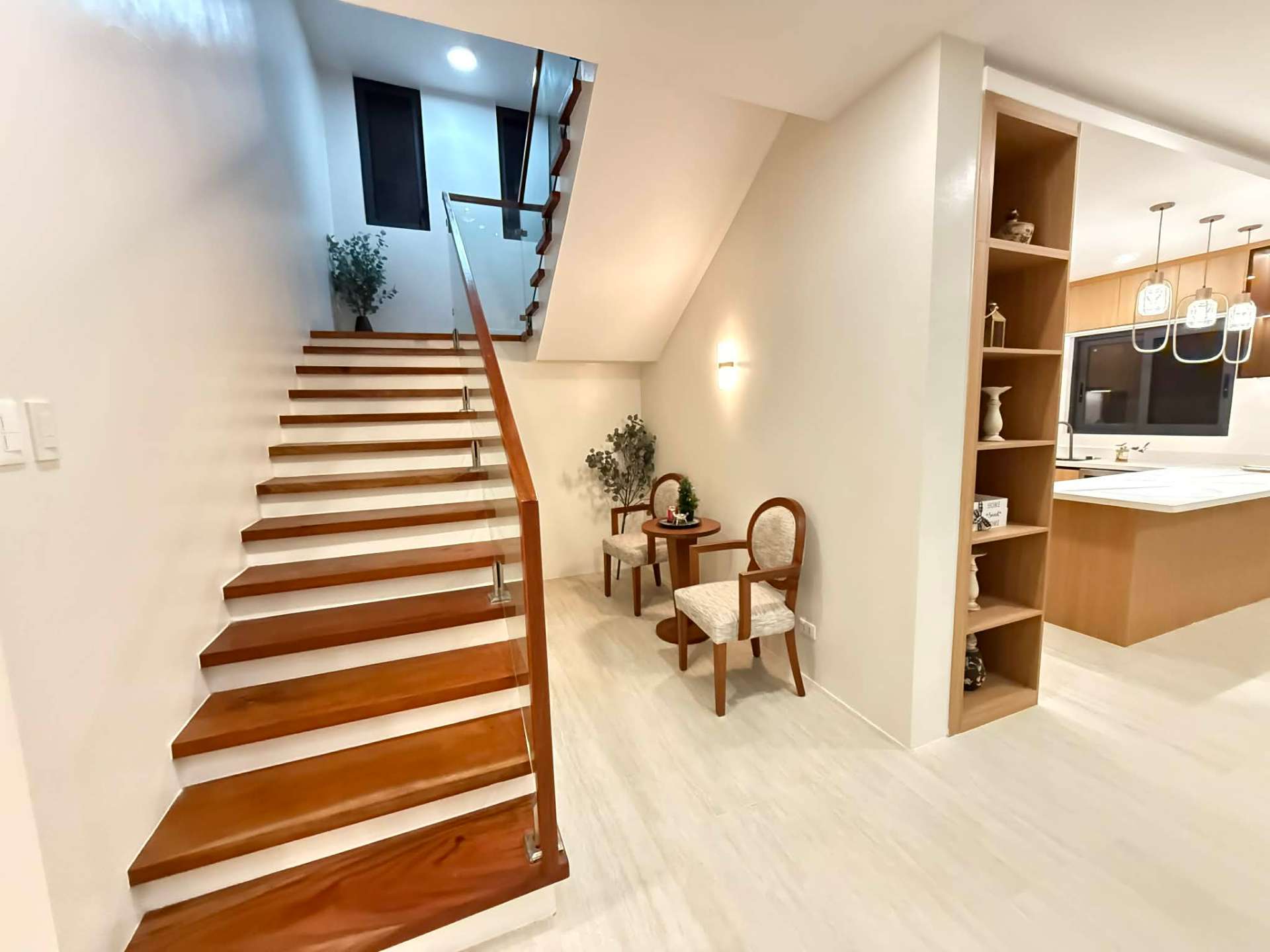Solid wood staircase with glass balustrade beside a built-in display shelf