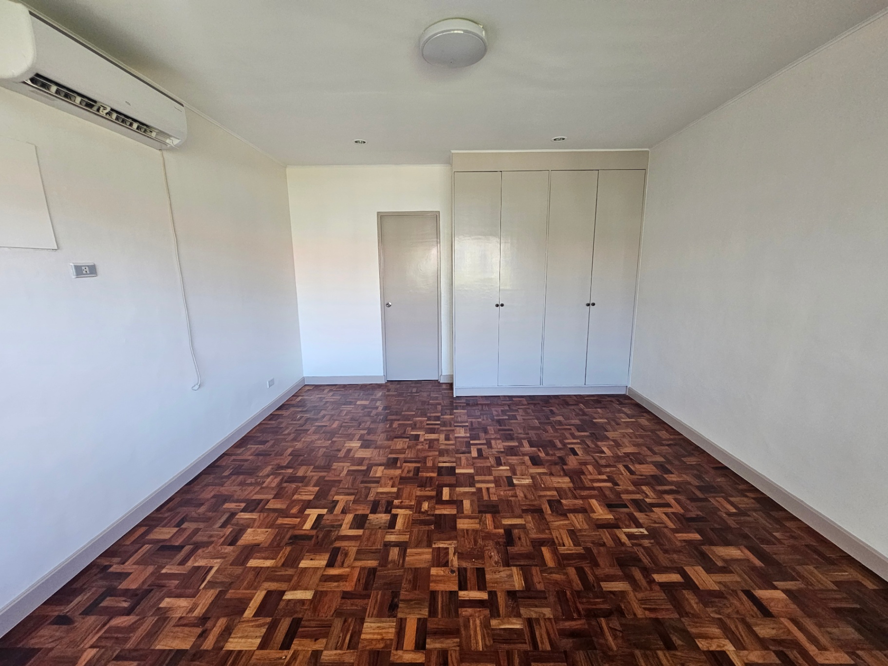 Bright bedroom with herringbone parquet and full-height white wardrobe