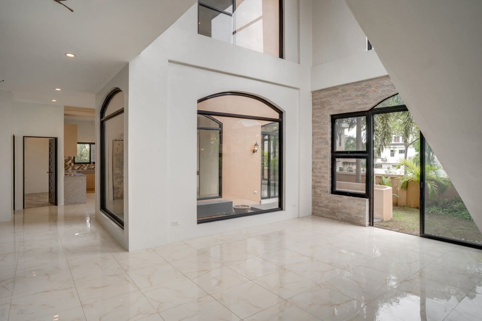 Double-height great room with arched atrium window and marble flooring