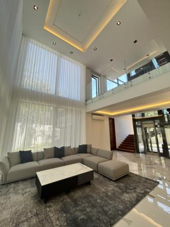 Double-height living room with sheer drapery, marble floors and glass-railed landing