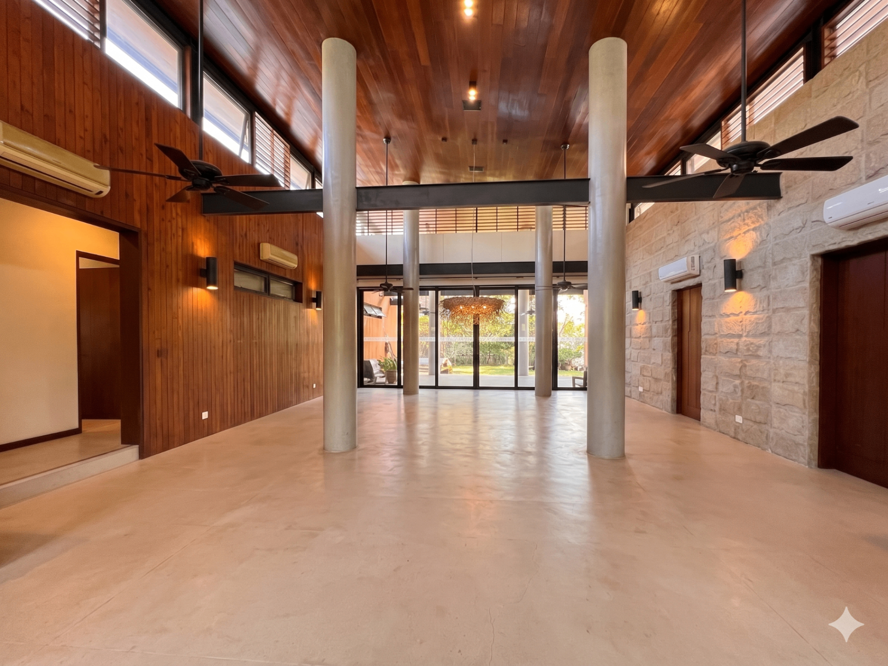 Grand atrium with twin columns, wood ceiling and stone wall opening to the garden