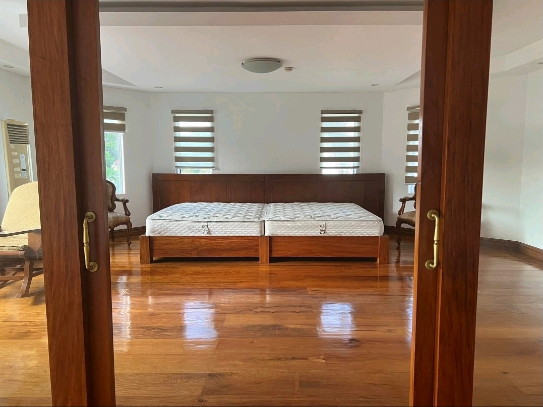 Spacious primary bedroom with polished wood floors