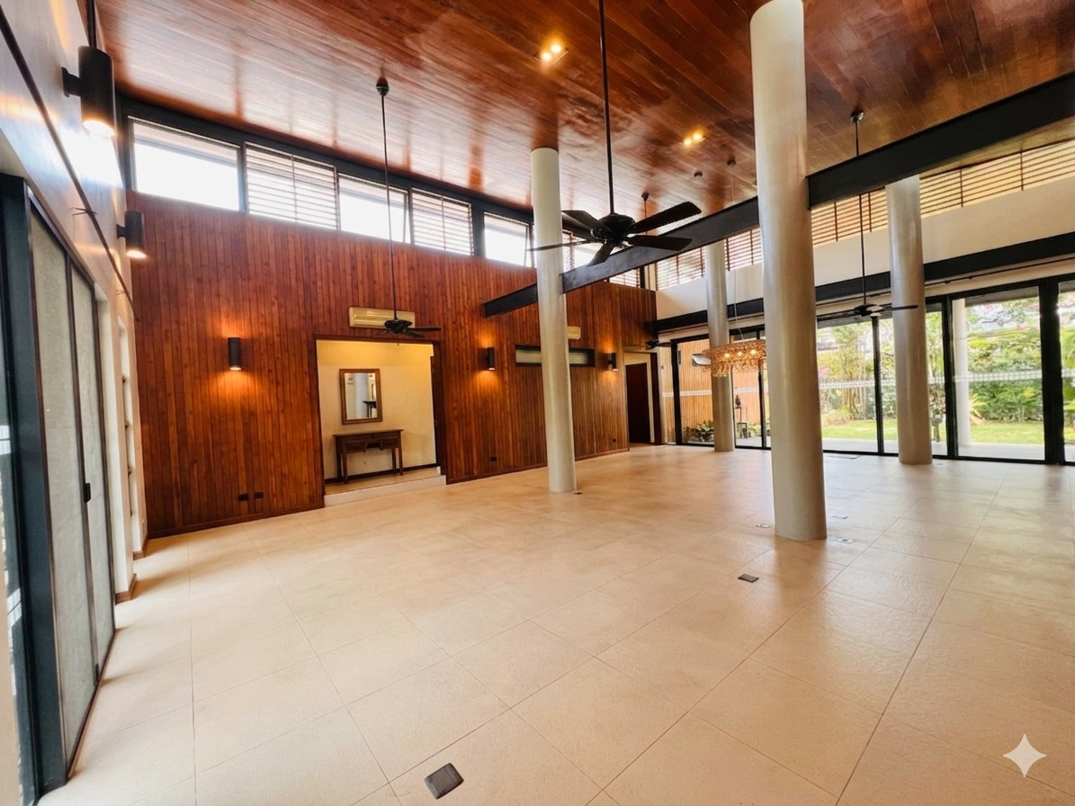 Double-height living pavilion with wood-clad ceiling, concrete columns and floor-to-ceiling sliding doors
