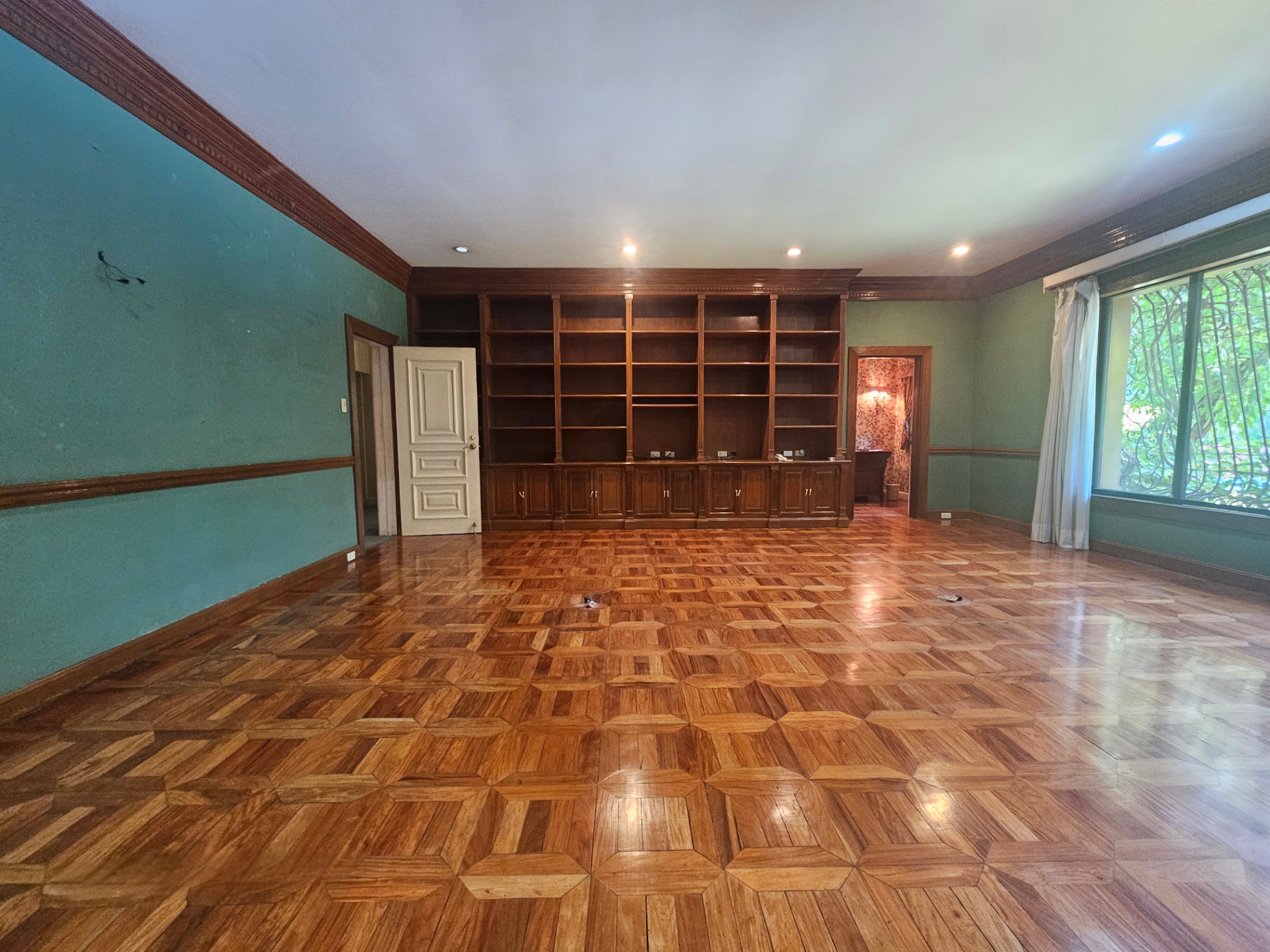 Wood-paneled library or study with built-in shelving and garden-facing window