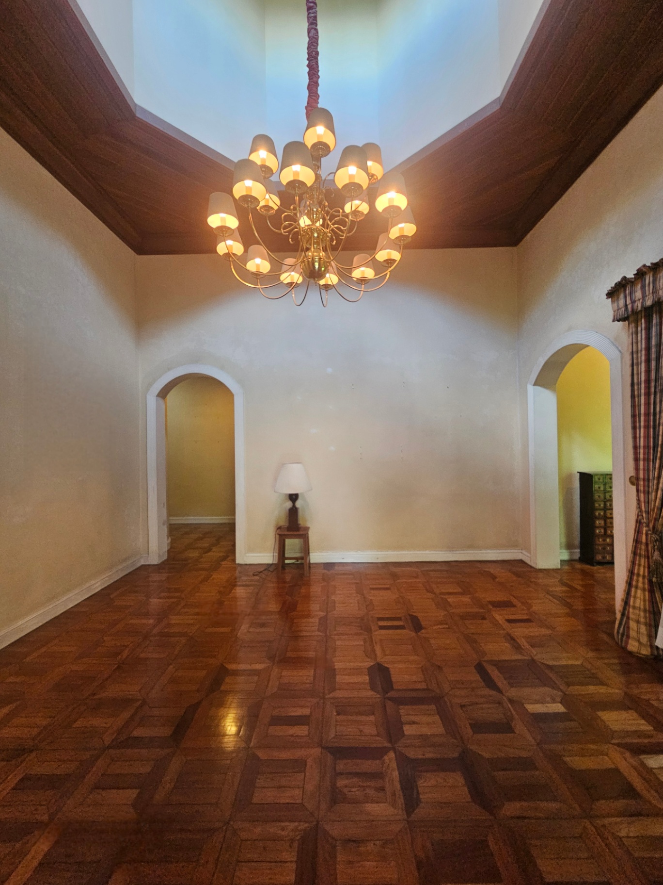 Double-height formal foyer with grand chandelier and arched passageways