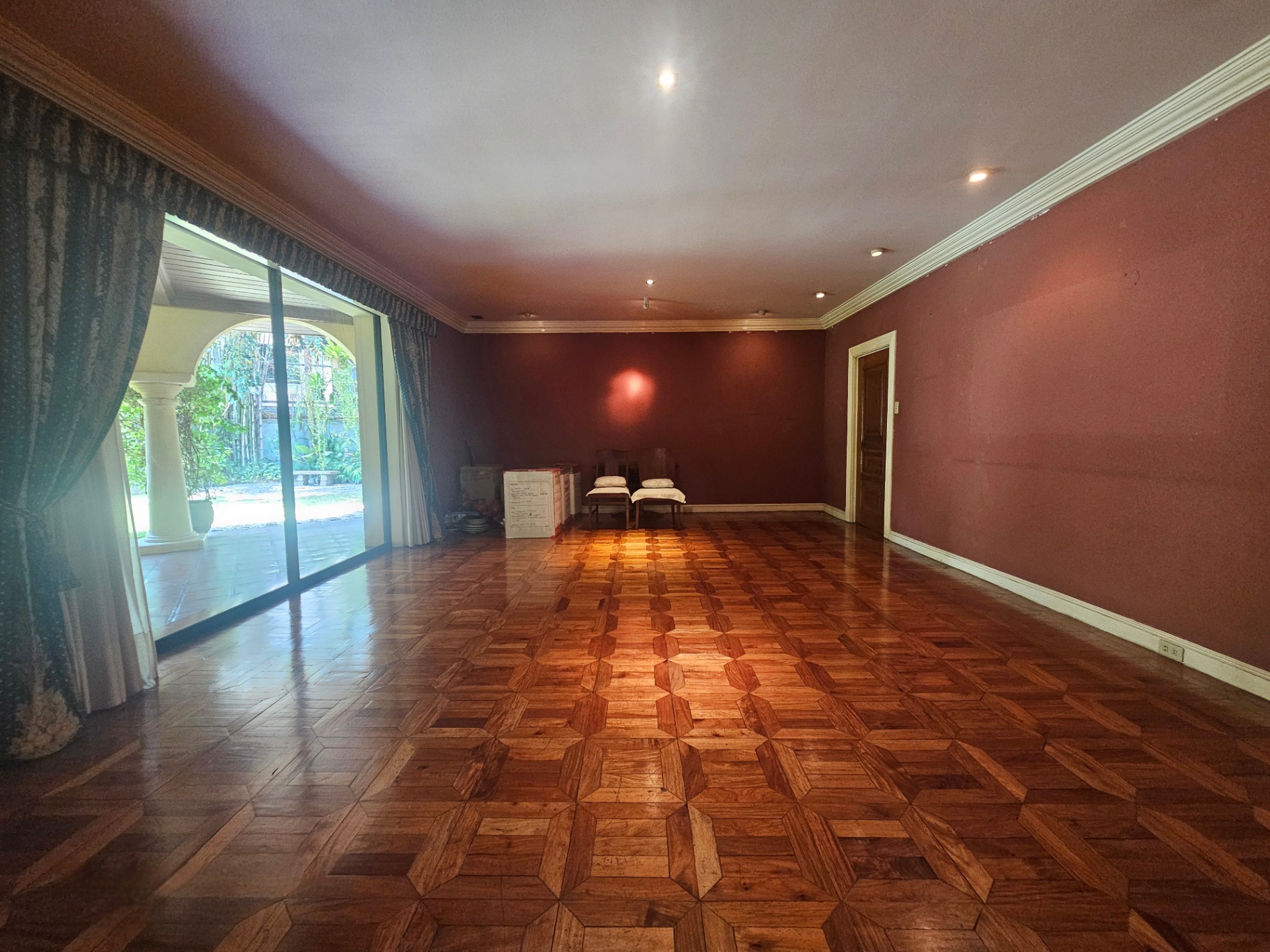 Formal living room with parquet flooring opening to the covered lanai and garden