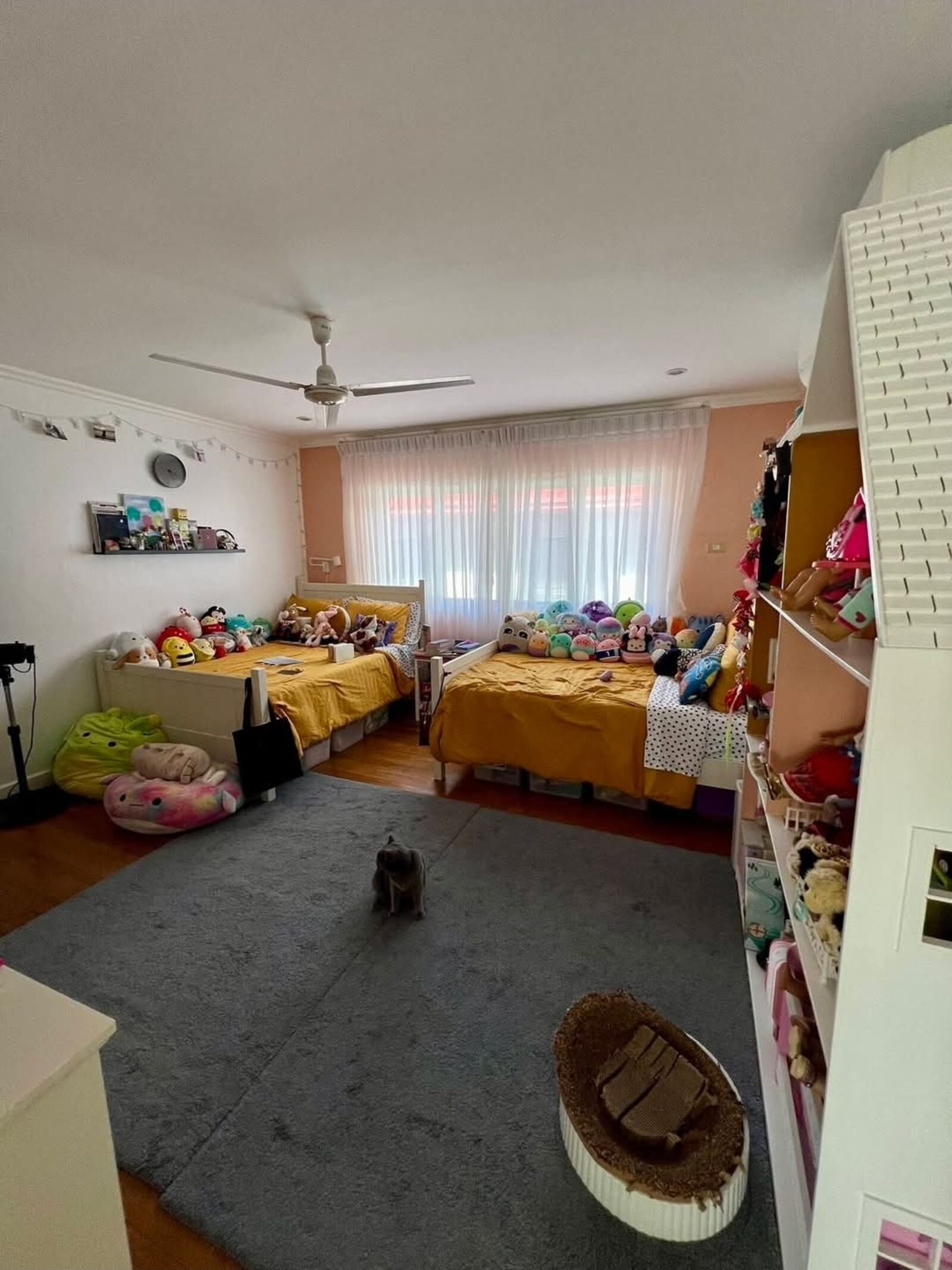 Large twin bedroom with built-in shelving and warm natural light