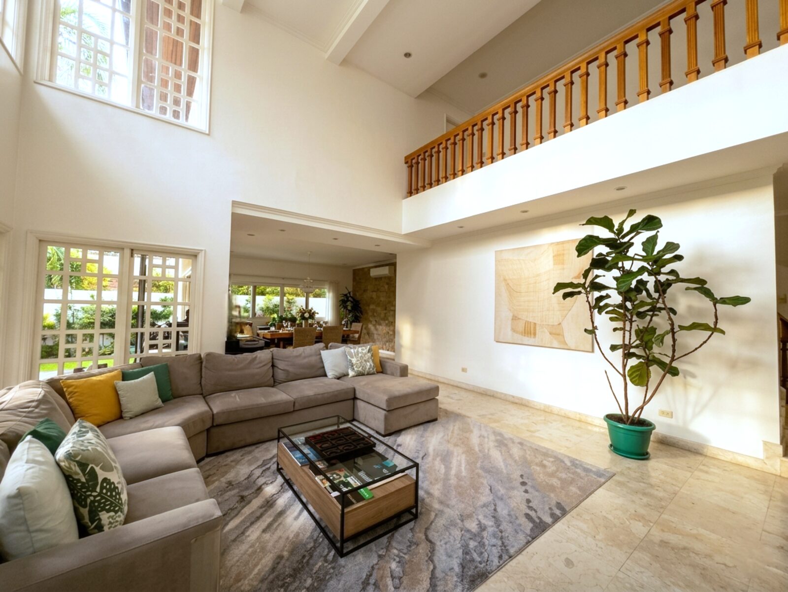 Soaring double-height living room with wooden mezzanine balustrade and marble floors
