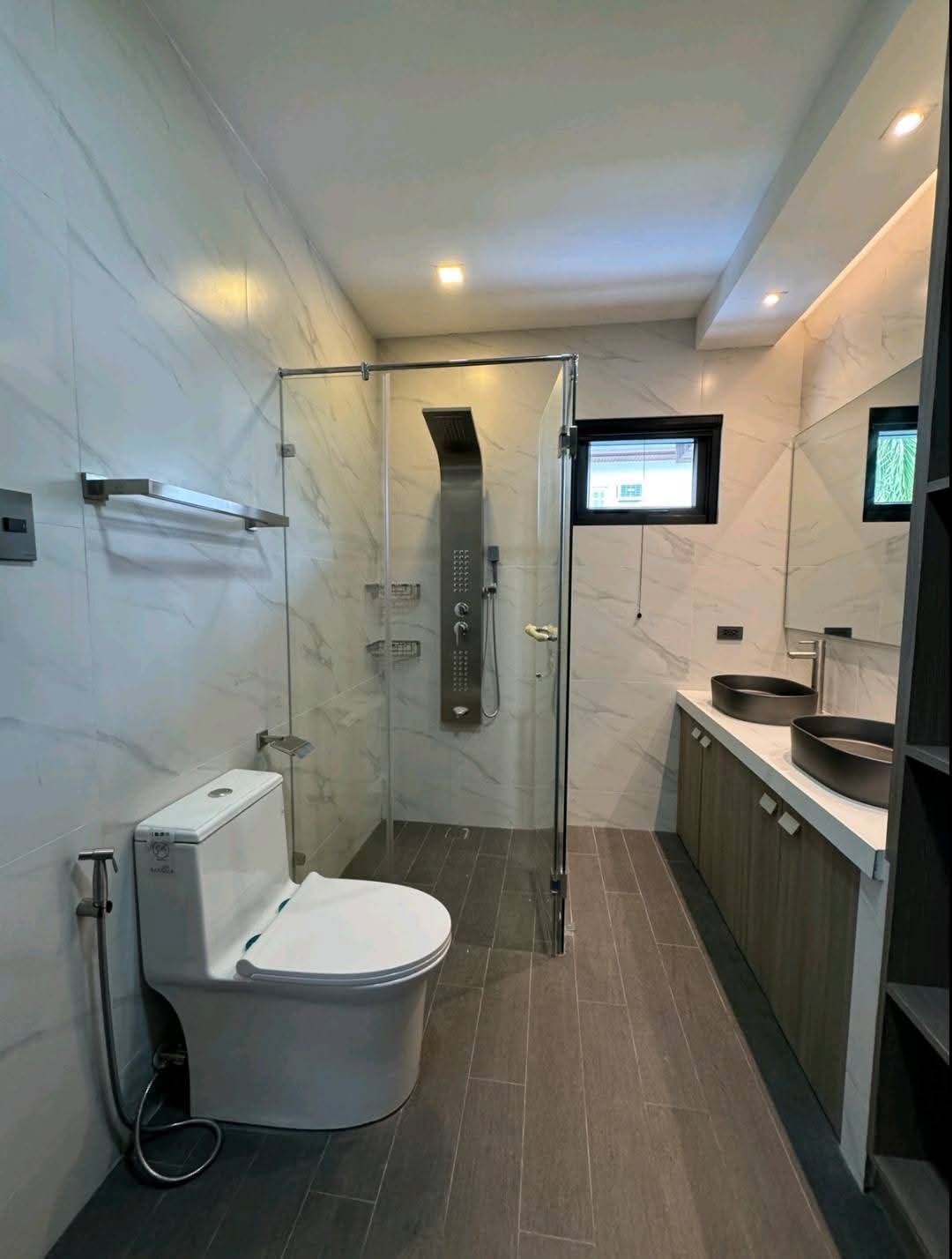 Master bath with marble cladding, twin vessel sinks and rain shower