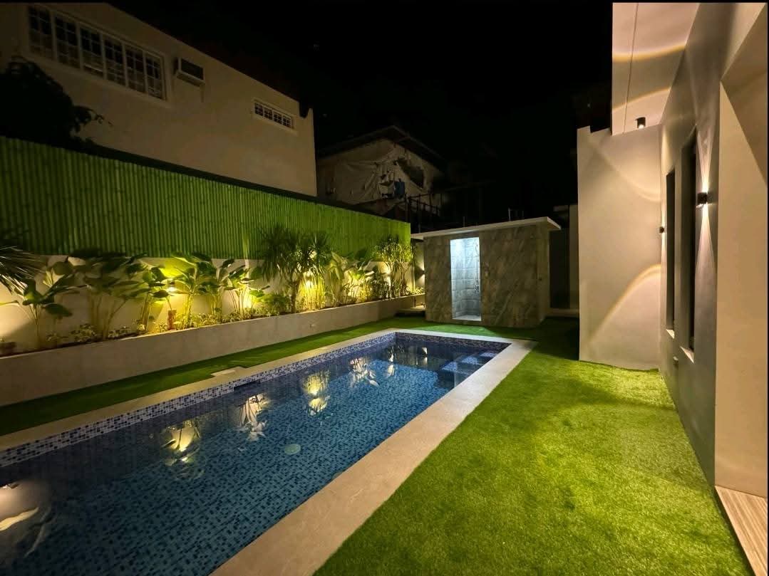 Mosaic-tiled pool illuminated at dusk against bamboo screens