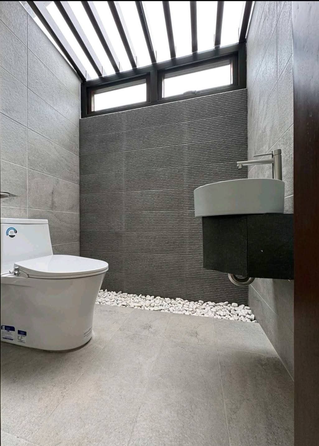 Second powder room with textured stone wall and slatted skylight