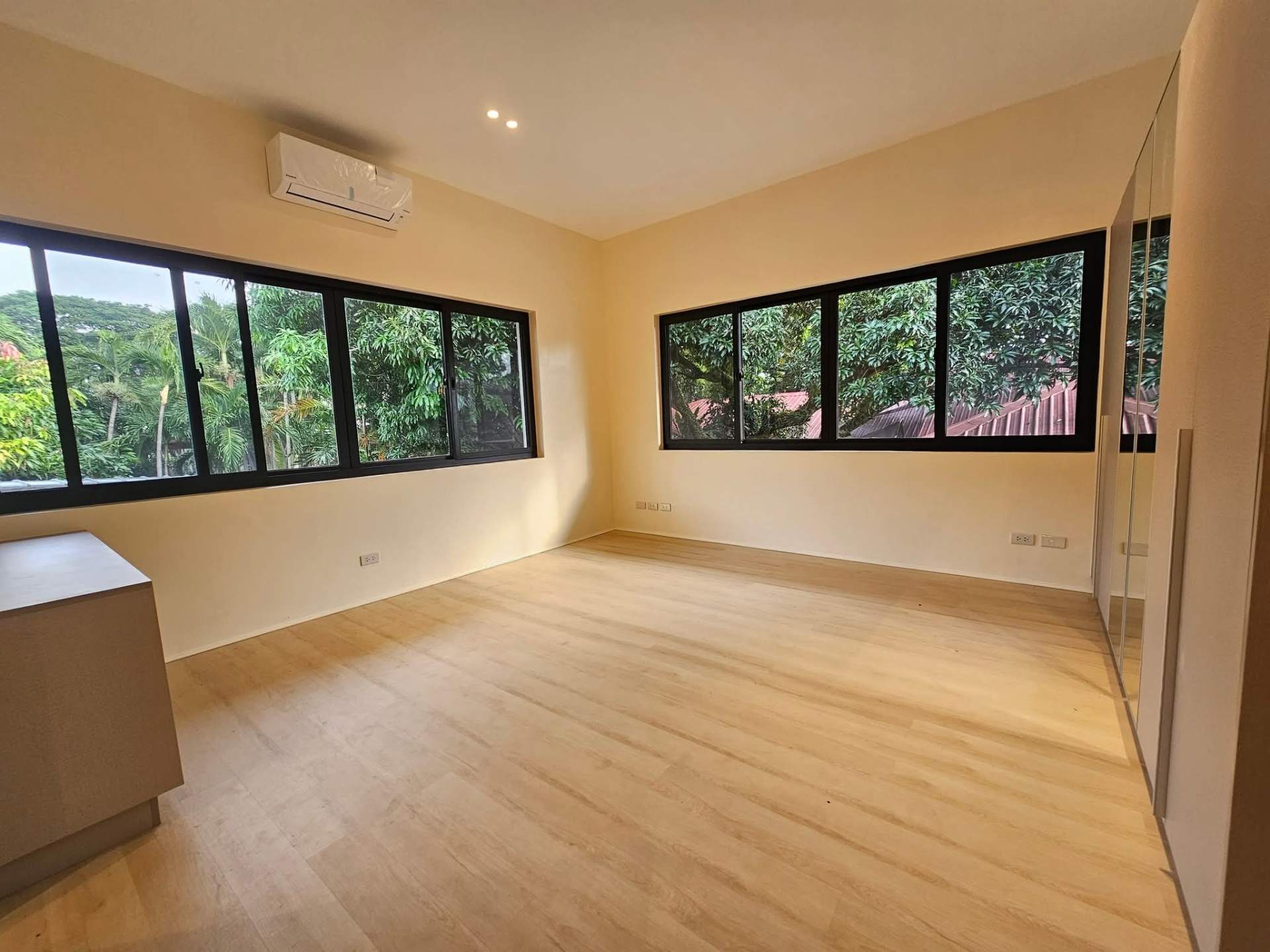 Bedroom with mirrored closets and panoramic garden windows