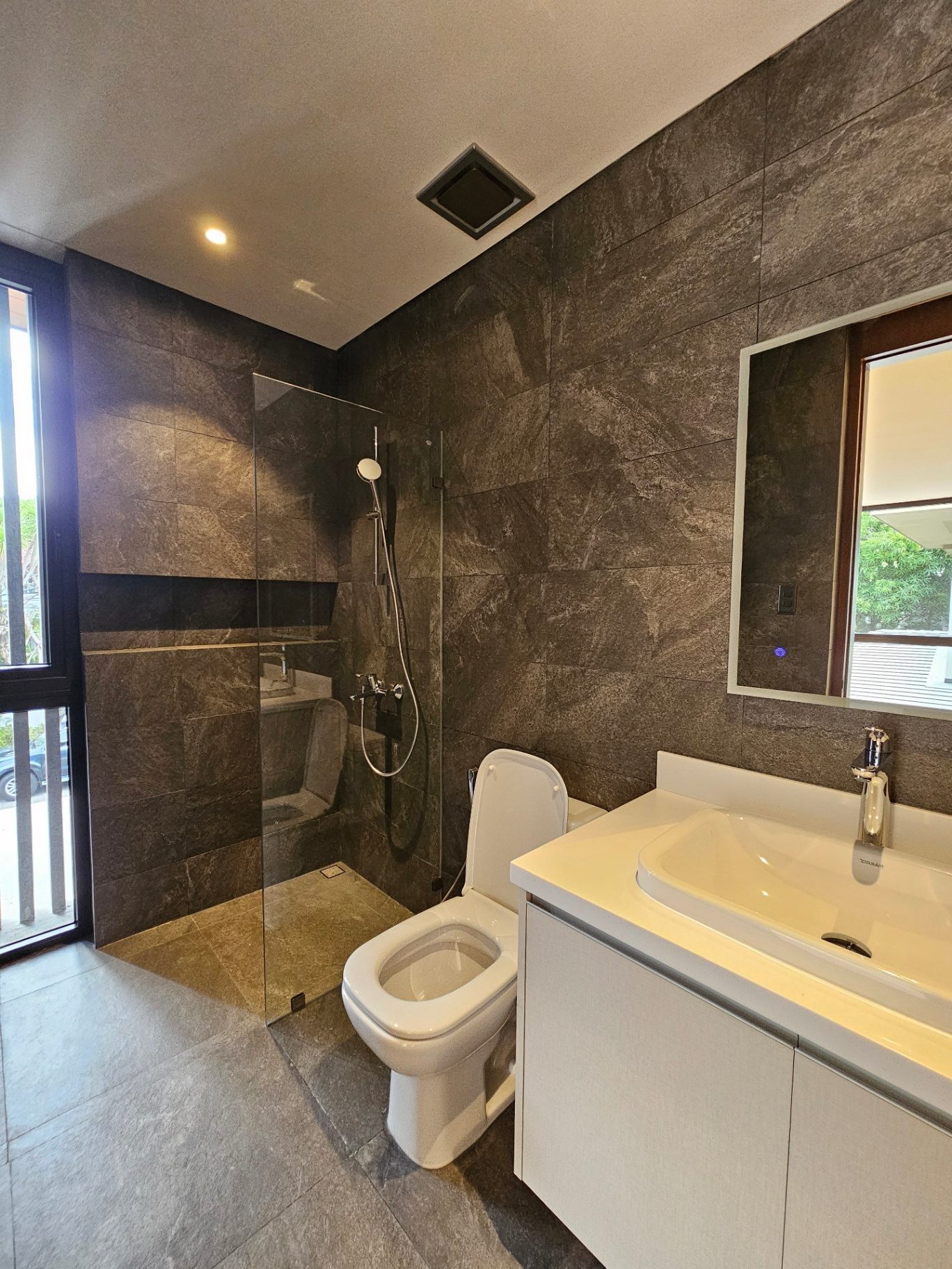 Stone-clad bathroom with walk-in rain shower and floating vanity