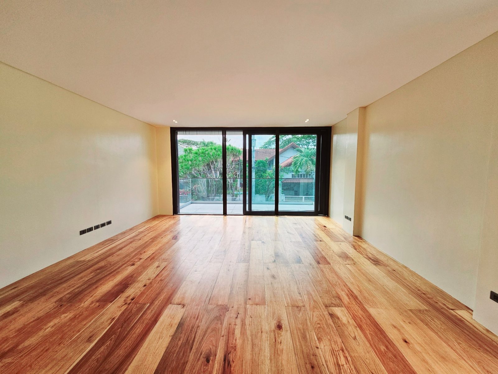 Bright bedroom with hardwood floors and full-height glass opening to a balcony